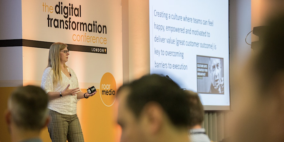 A women standing in a conference hall to speak about digital transformation